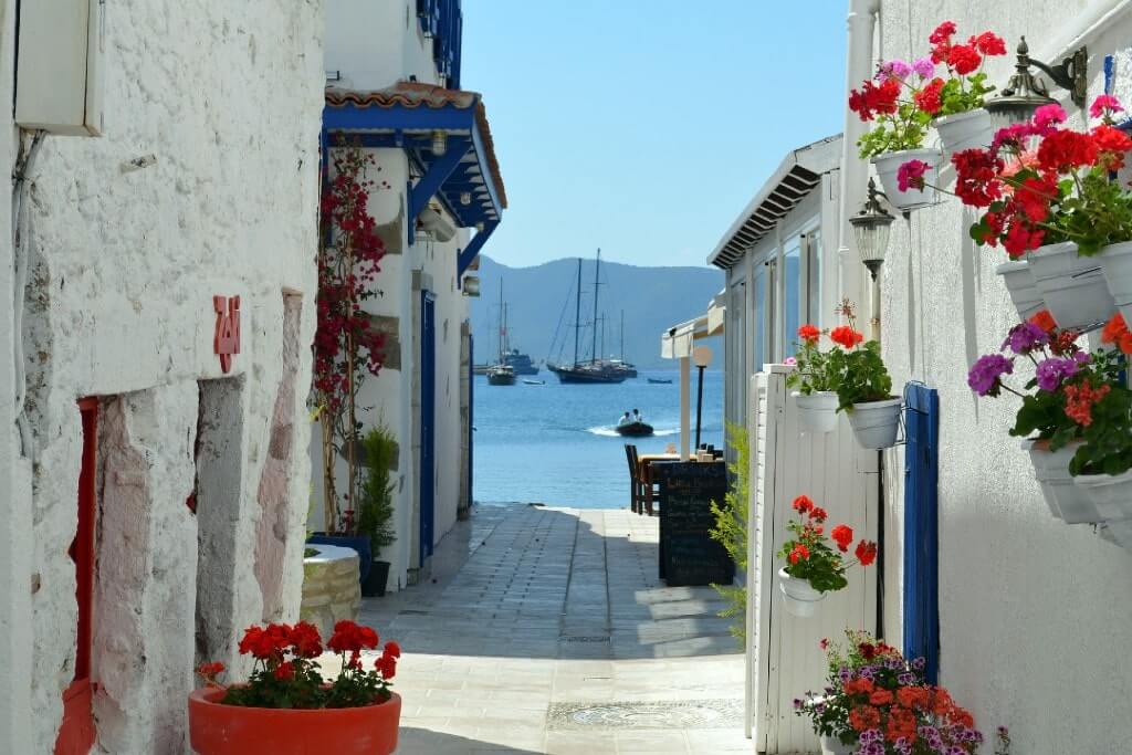 Viuzza bianca e ornata di fiori della cittadina di Bodrum, in Turchia, che si dirige al mare.