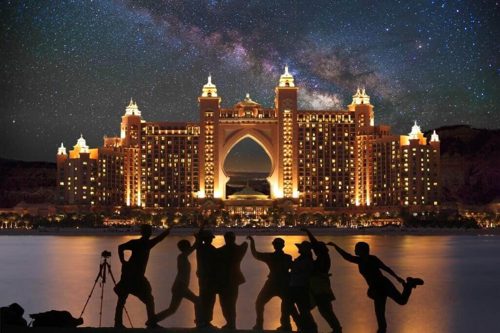 Gruppo di amici si scatta una foto di notte davanti all'Atlantis The Palm, a Dubai, in viaggio.