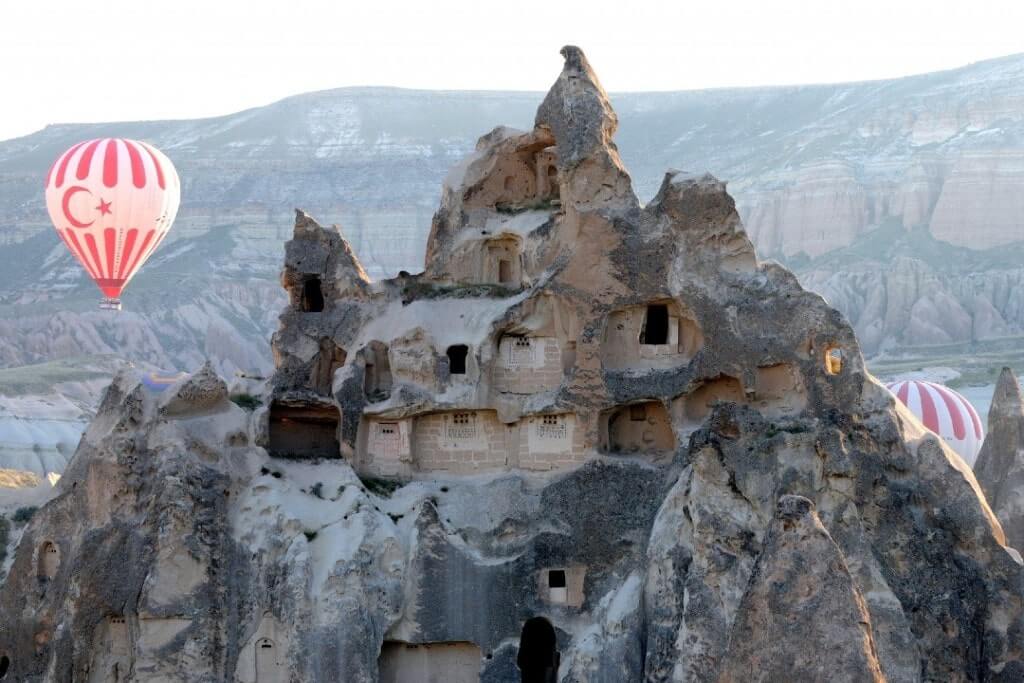 Una mongolfiera passa accanto a uno dei Camini delle Fate, in Cappadocia, in Turchia.