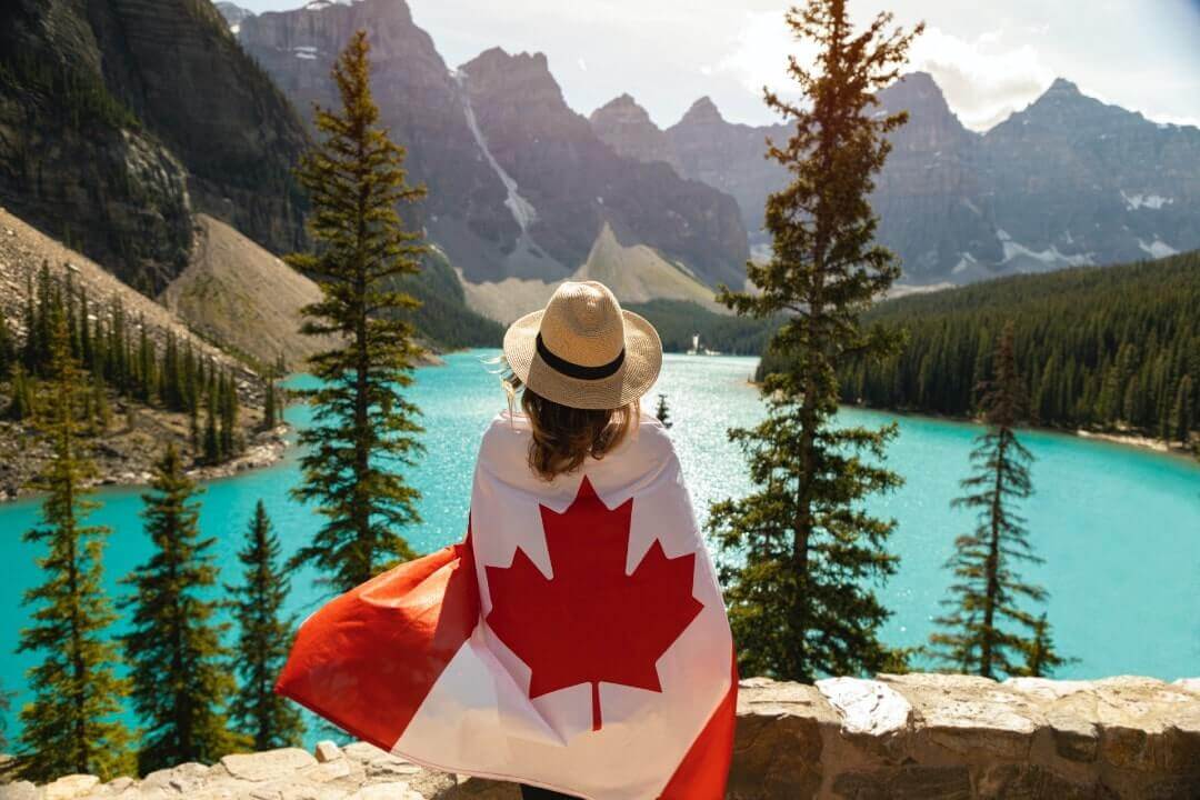 Turista con una bandiera del canada sul Lago Moraine, al Parco di Banff. Cosa vedere in Canada?