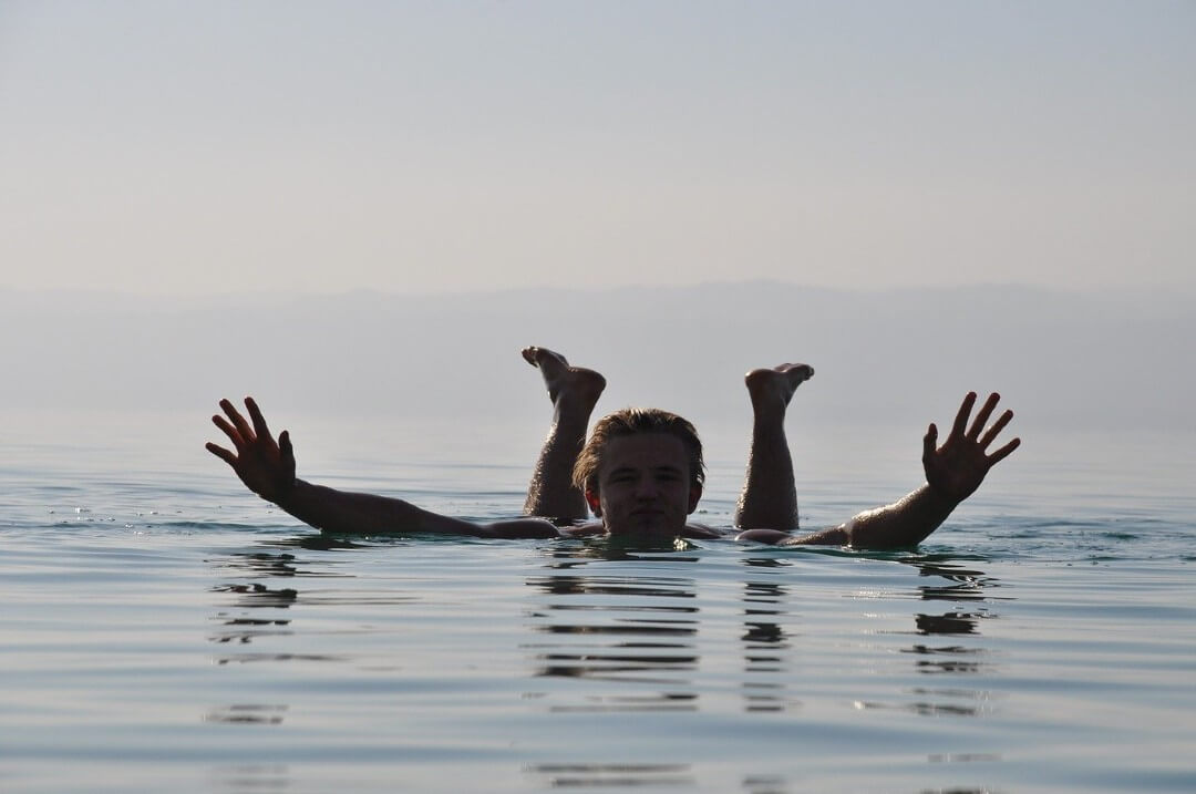 Un uomo fa il bagno e galleggia sull'acqua del Mar Morto in Giordania.