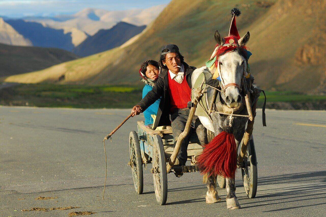 Due persone su un carro in Tibet, luogo da visitare con un'assicurazione viaggio Nepal