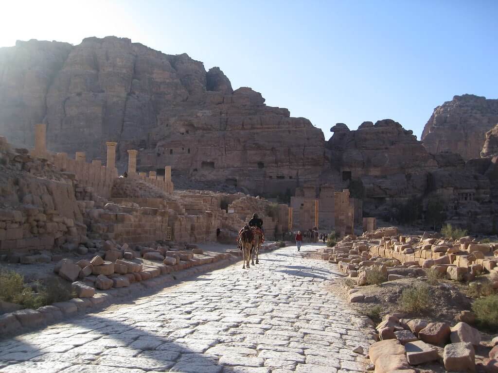 Un uomo a cammello percorre la Strada delle Colonne a Petra.