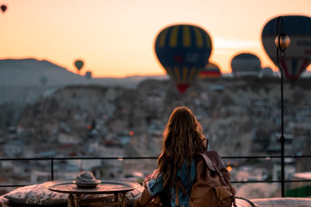 Una turista osserva le mongolfiere in Cappadocia. In vacanza serve l'assicurazione viaggio Turchia.