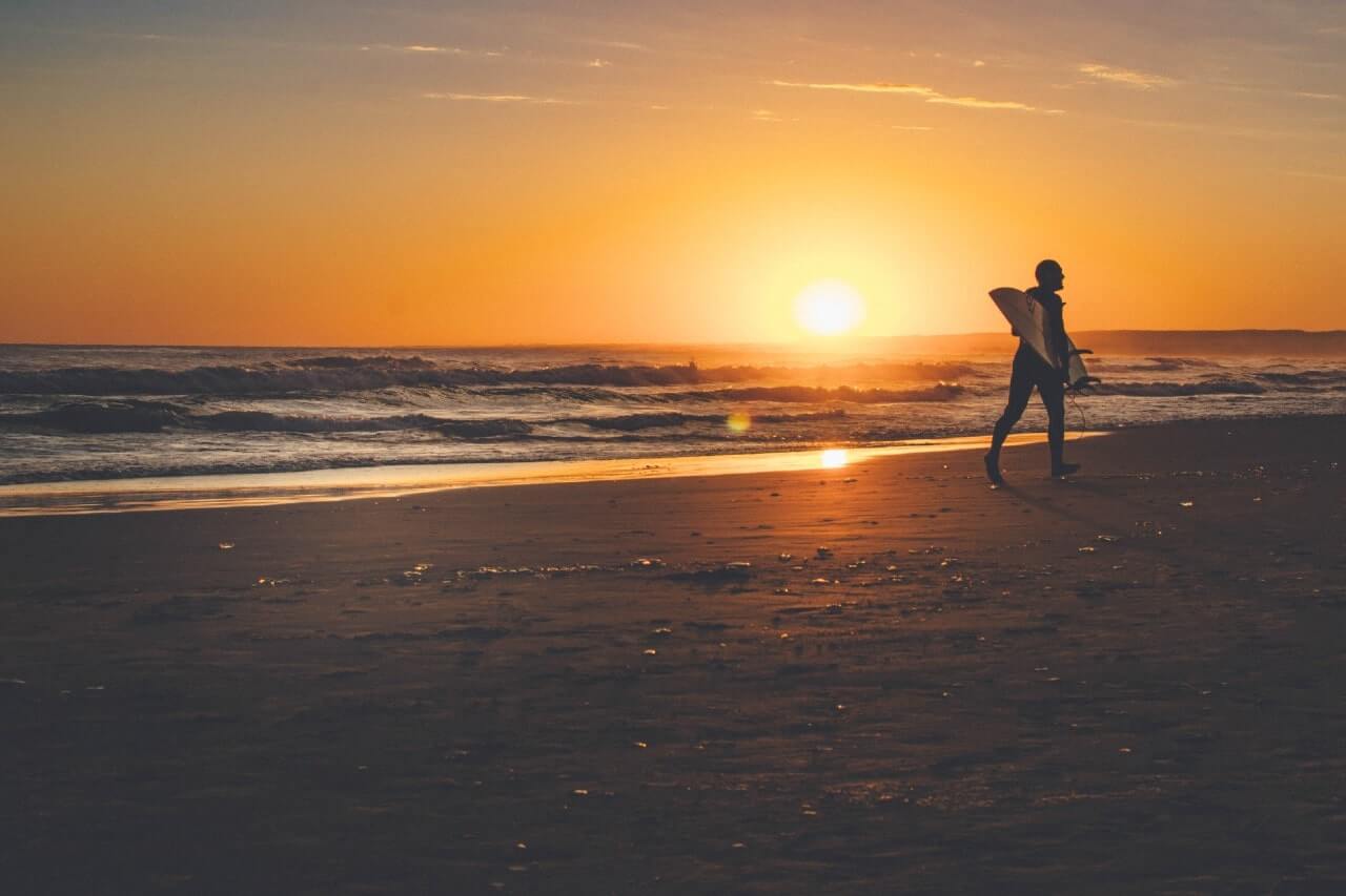 Un surfista corre sulla spiaggia di Cabo Polonio, in Uruguay, al tramonto.