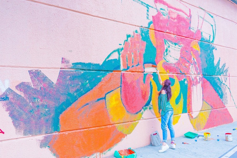 Una street artist compone graffiti sulle mura di Medellin. Scopri se la Colombia è una nazione sicura con le guide di Amerigo.it