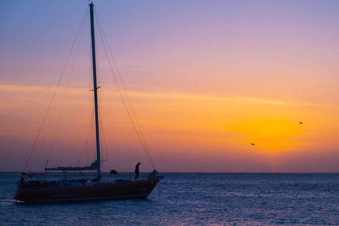 Una barca in mezzo al mere di Aruba al tramonto.