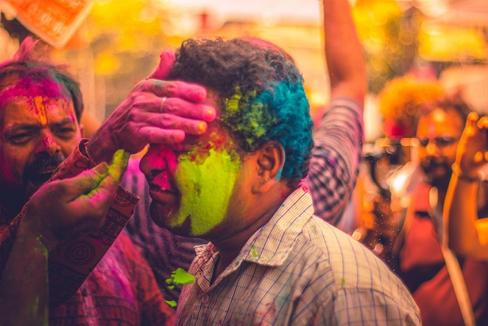 Un uomo si lascia cospargere il viso di polveri colorate durante la festa dei colori in India