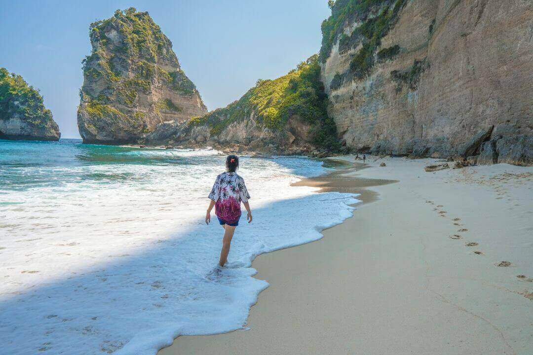 Donna cammina lungo la spiaggia di Nusa Penida a Bali.