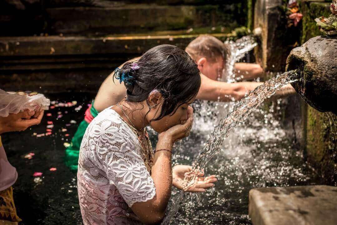 Un uomo e una donna si bagnano alle piscine delle Sorgenti sacre di Tirta Empul, a Bali.