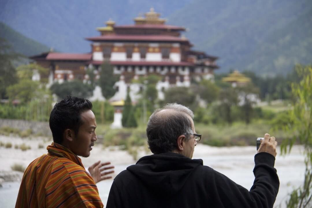 Turista e una guida osservano il Punakha Dzong, le regole del turismo e quando andare in Bhutan.