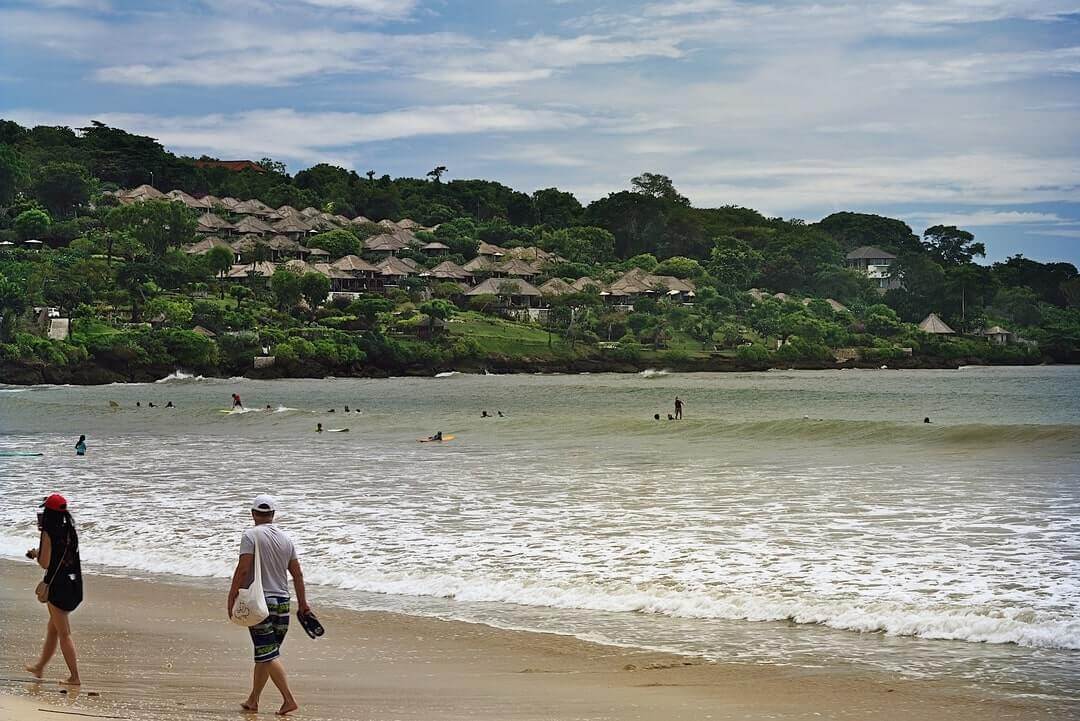 dei turisti lungo la spiaggia di Jimbaran a Bali.