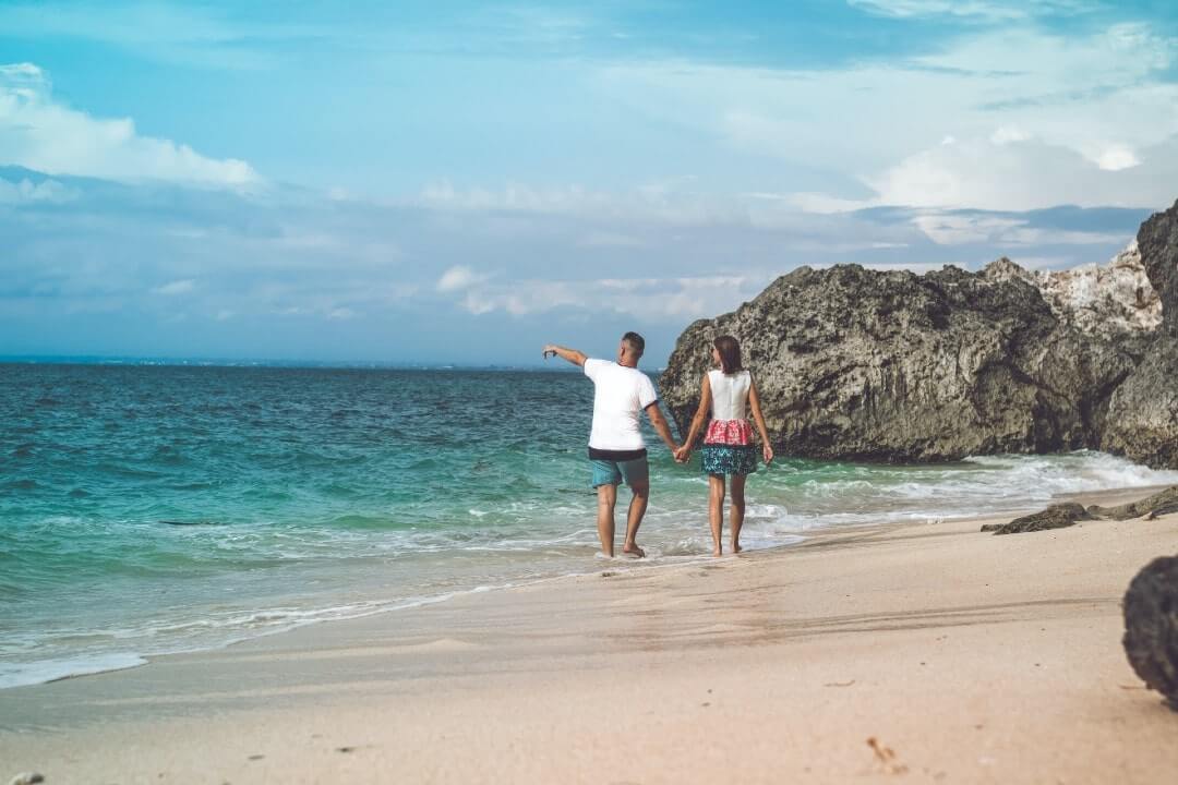 Coppia cammina su una spiaggia a Bali al sole di agosto.