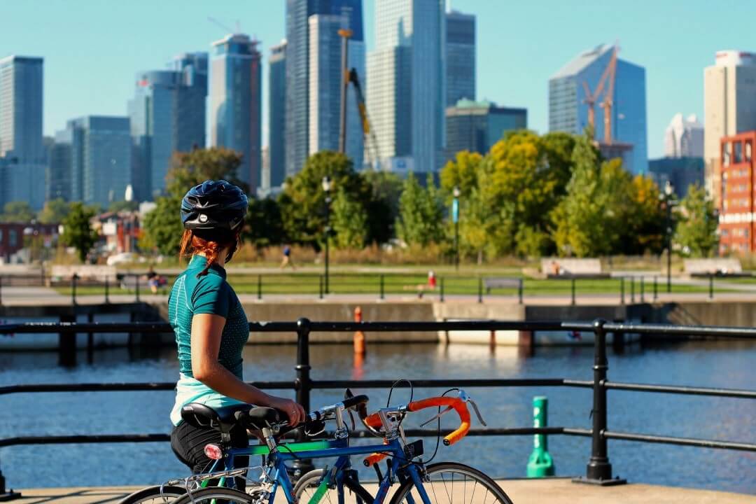 Una donna in bicicletta osserva lo skyline di Montréal.